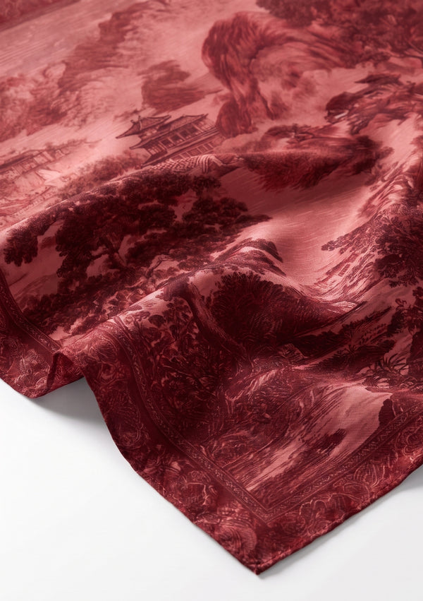 Corner detail of the Crimson Dusk silk scarf showing the finely rolled edge and the ornamental border framing the pagoda landscape print