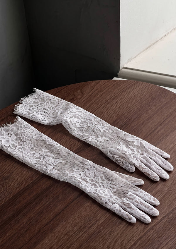 Pair of Etherea white floral lace opera gloves laid flat, showing the full-fingered cut and eyelash-fringe cuff