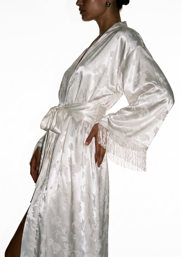 Side view of the Moonveil robe with the sash knotted at the waist and fringe falling from the raised sleeve