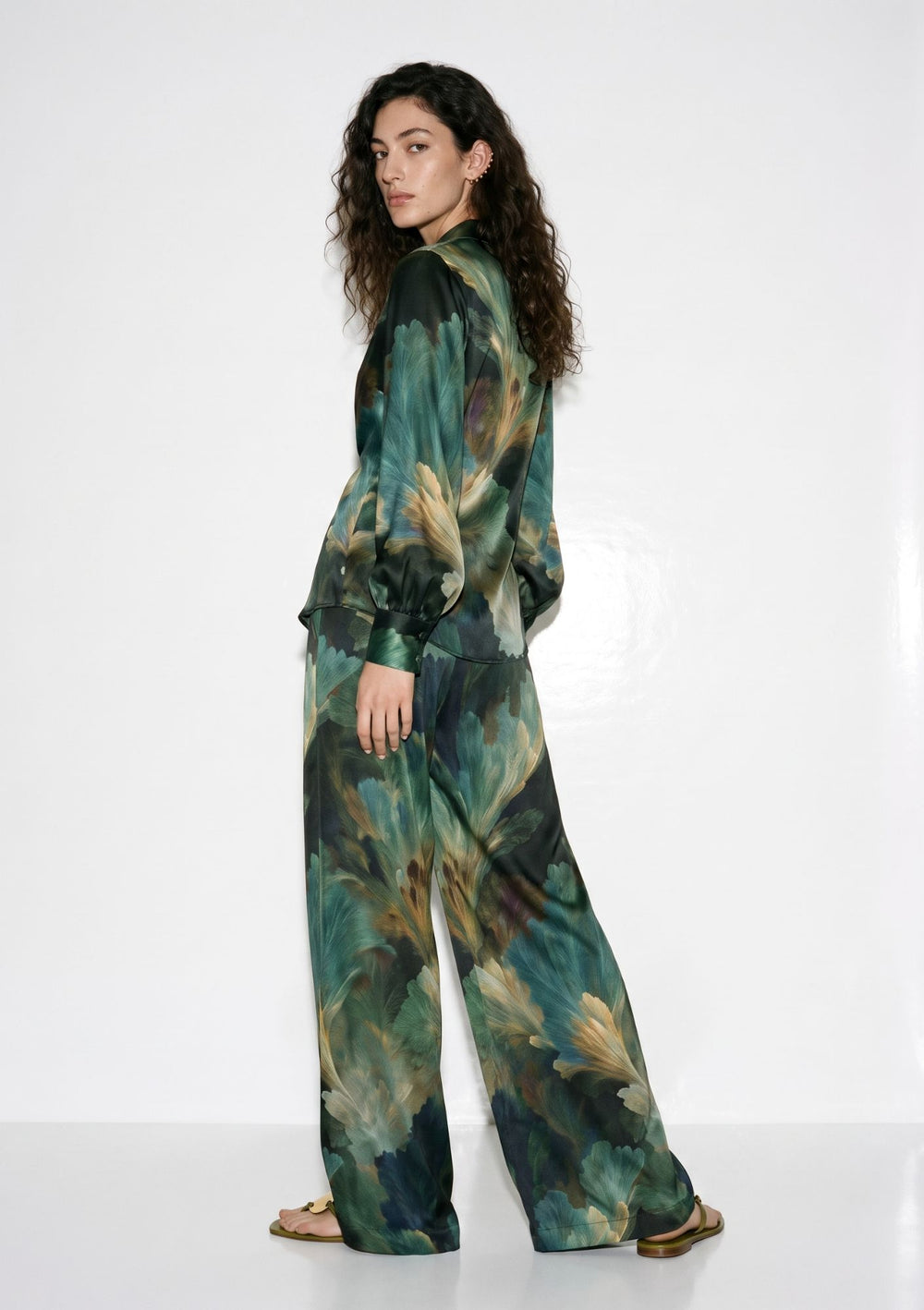 Green botanical print silk pajama set on model, front view, tie-front shirt with deep V neckline knotted at the waist and matching wide-leg trousers