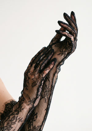 Close-up of the Eclipse black floral lace opera glove on a raised arm, showing the sheer second-skin fit and ruffled trim at the top opening