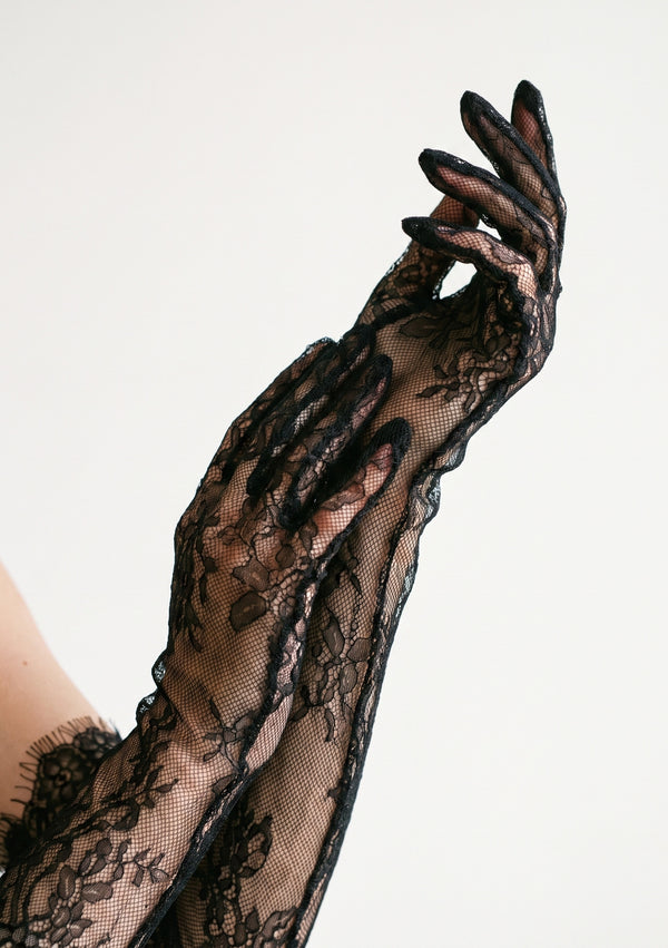 Close-up of the Eclipse black floral lace opera glove on a raised arm, showing the sheer second-skin fit and ruffled trim at the top opening