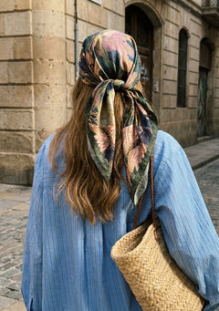Selene silk scarf worn as a head scarf tied at the nape, the green and blush garden print falling over the shoulders