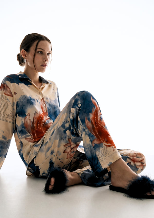 Sumi Set worn seated on the floor, printed satin shirt and wide-leg trousers draping with feather slides