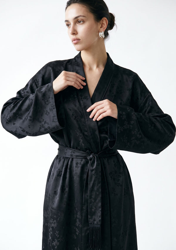Three-quarter view of the Tenebrae Robe, deep V shawl collar and belt knotted at the waist with fringe at the ends
