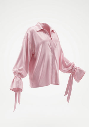 Petal Blouse product shot: pale pink viscose blouse with a shirt collar, full sleeves and ruffled cuffs tied with ribbon bows.