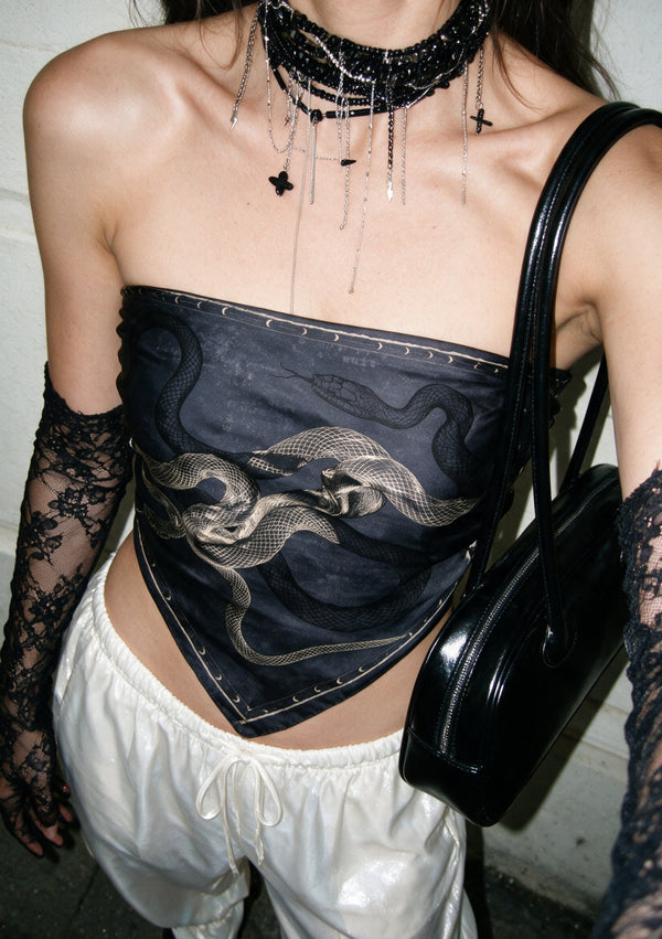 Model wearing the Temptation silk scarf tied as a strapless bandeau top with white parachute trousers, black lace gloves and a patent shoulder bag