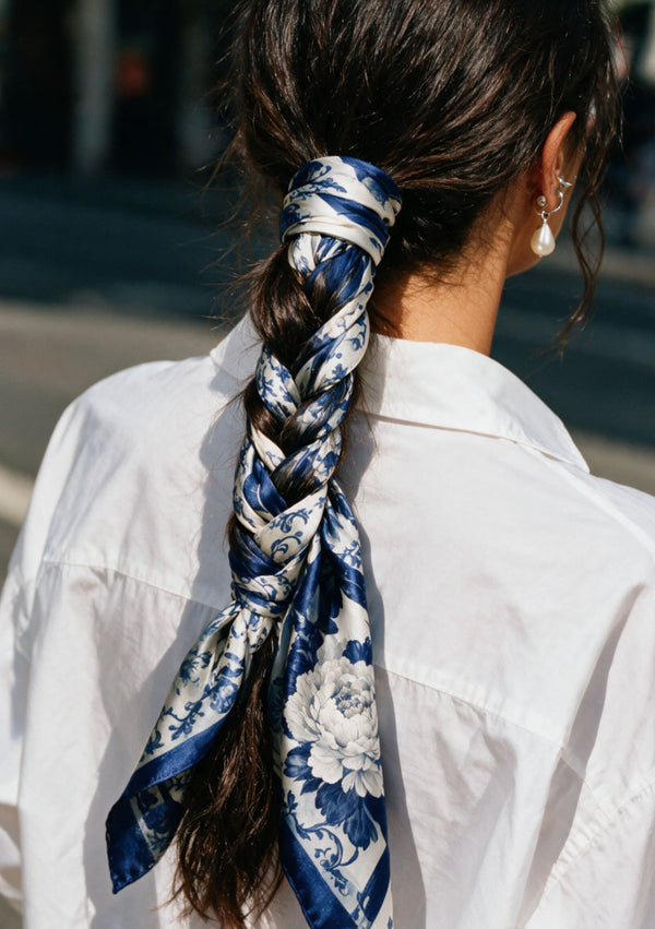 Mirage Peony Scarf in blue and white silk woven through a long braided ponytail, worn with a white shirt