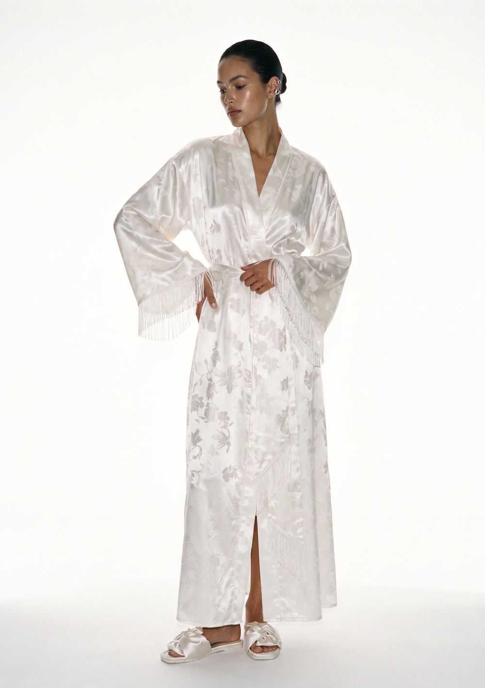 Moonveil ivory satin jacquard robe on model, floor-length wrap tied at the waist, long silk fringe falling from each wide sleeve