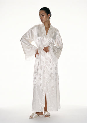 Moonveil ivory satin jacquard robe on model, floor-length wrap tied at the waist, long silk fringe falling from each wide sleeve