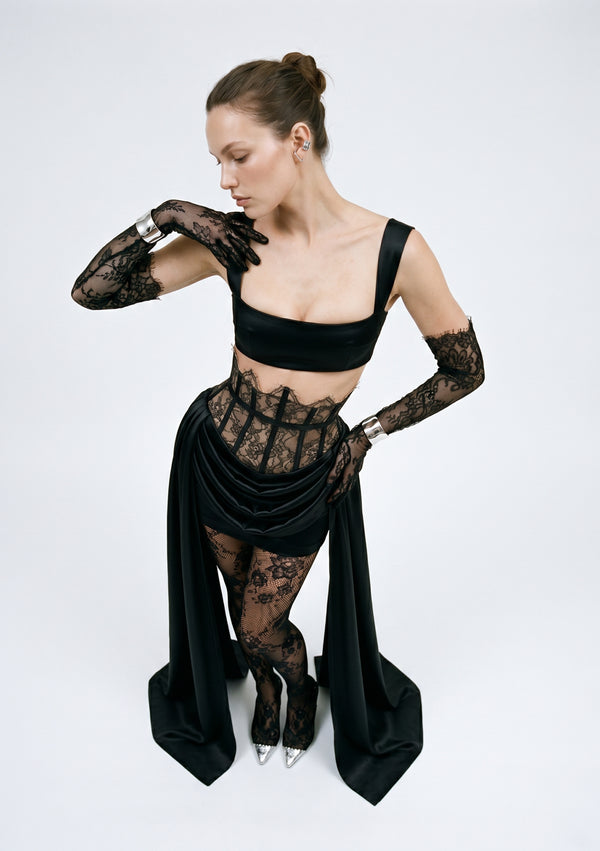 Black satin Baccara corset-waist mini skirt with draped satin and side trains, on model