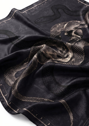 Draped detail of the printed silk scarf catching the light, with twisting serpents, hazy texture and the crescent moon border