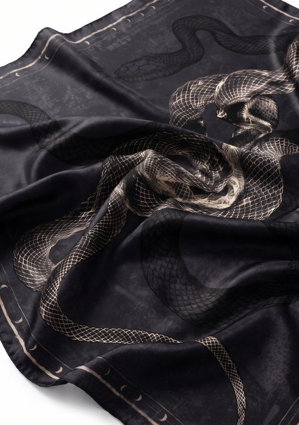 Draped detail of the printed silk scarf catching the light, with twisting serpents, hazy texture and the crescent moon border