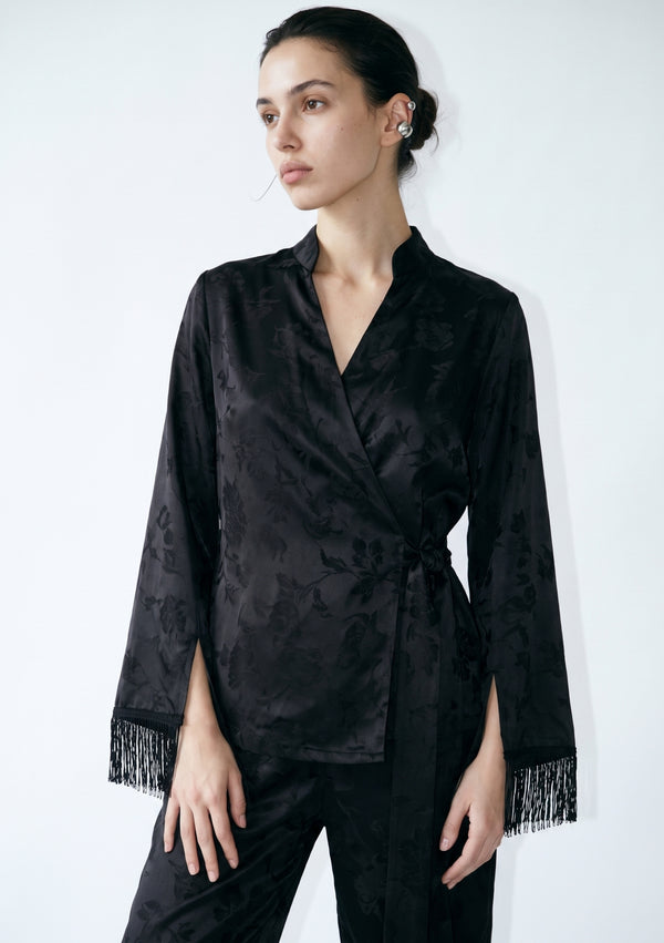Waist-up view of the Tenebrae Set, black jacquard wrap top knotted at the side with silk fringe falling from both sleeve cuffs