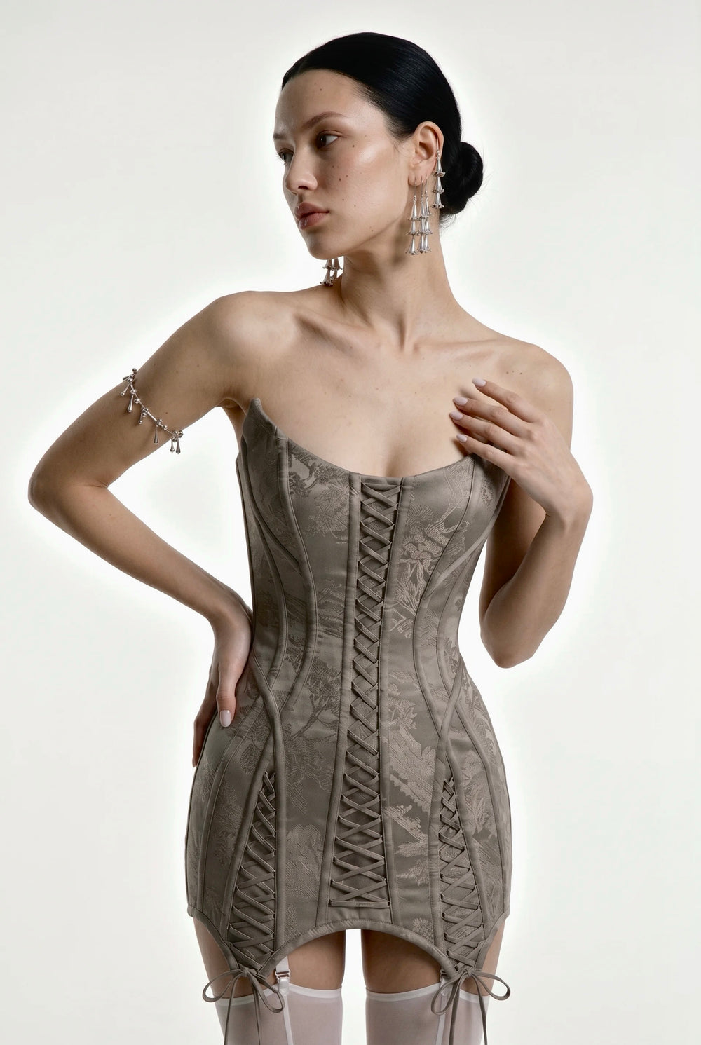Strapless grey jacquard Lucentia corset mini dress with front lace-up panels and a pointed tie hem, front view on model