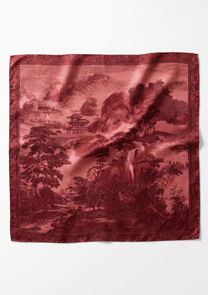 Crimson Dusk Scarf flat lay, large square silk scarf printed with a deep red engraved landscape of mountains, pagodas and trees inside an ornamental border