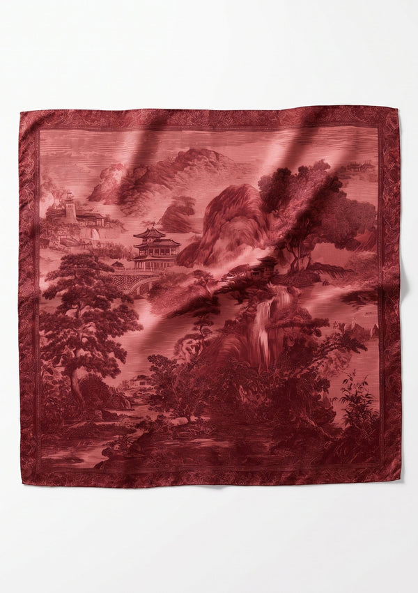 Crimson Dusk Scarf flat lay, large square silk scarf printed with a deep red engraved landscape of mountains, pagodas and trees inside an ornamental border