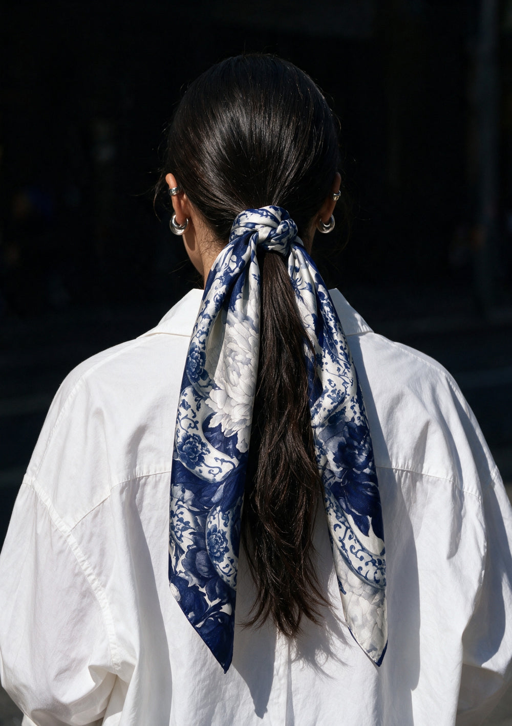 Mirage Peony Scarf knotted around a low ponytail with long printed ends falling over a white shirt