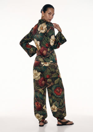Back view of the Eden silk set, showing the stand collar, the shoulder line of the wrap top and the garden print running the full length of the trousers