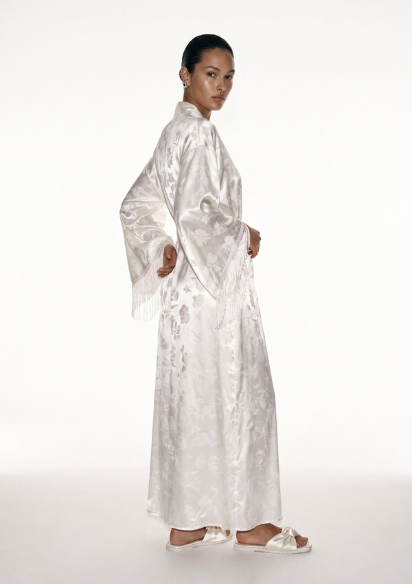 Moonveil robe in profile, floor-length ivory column with the fringed sleeve hanging along the body