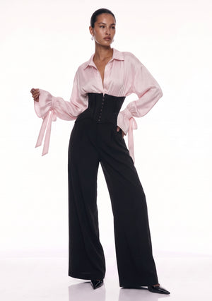 Full-length front view of black wide-leg corset trousers styled with a blush satin blouse.