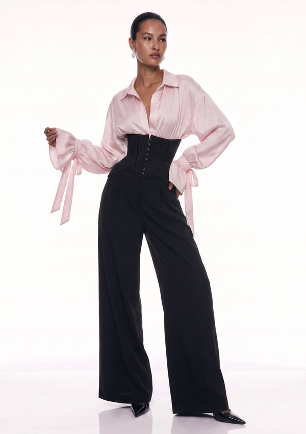 Full-length front view of black wide-leg corset trousers styled with a blush satin blouse.