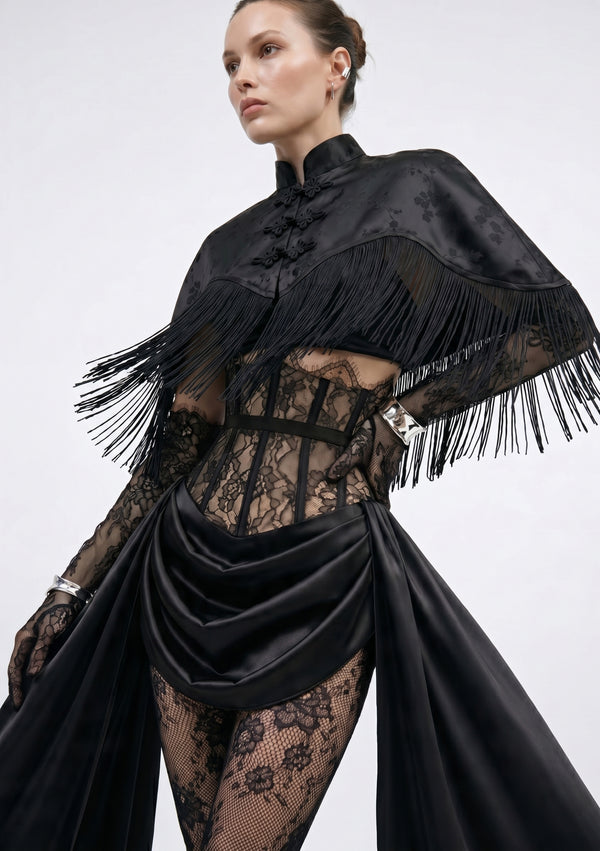 La Musa Baccara black satin-jacquard fringe capelet layered over the Baccara corset, three-quarter view