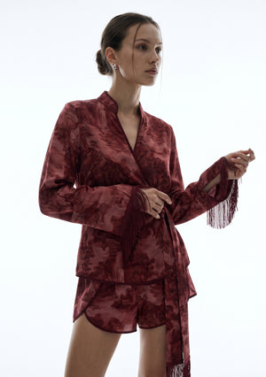 Crimson Dusk Mini Set, three-quarter view of the mandarin split neckline and elongated sleeves with silk fringe trim held in the hand