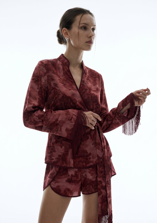 Crimson Dusk Mini Set, three-quarter view of the mandarin split neckline and elongated sleeves with silk fringe trim held in the hand
