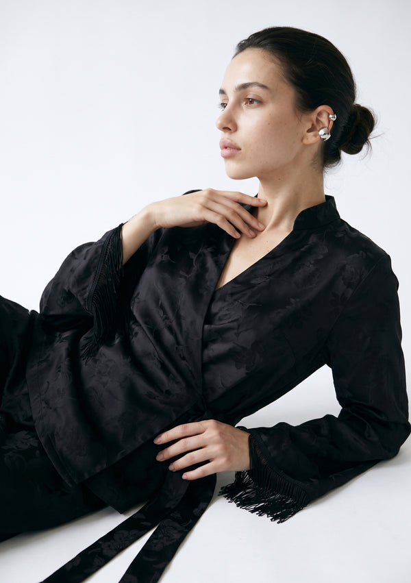 Model reclining in the Tenebrae Set, tonal floral jacquard weave and black silk fringe cuffs shown in close detail