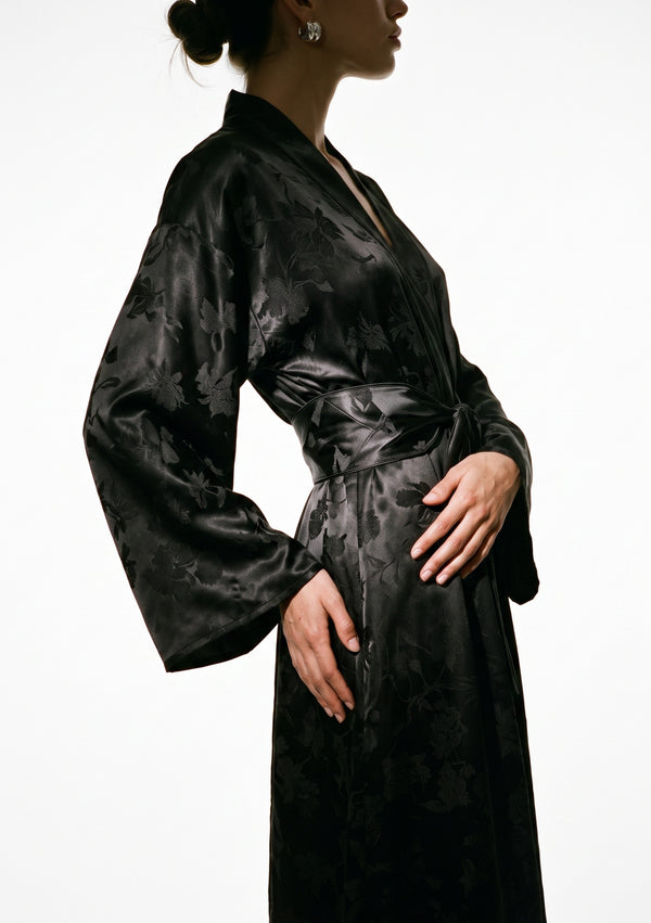 Side profile of the Tenebrae robe, wide bell sleeve and the structured wrap belt knotted at the side of the waist