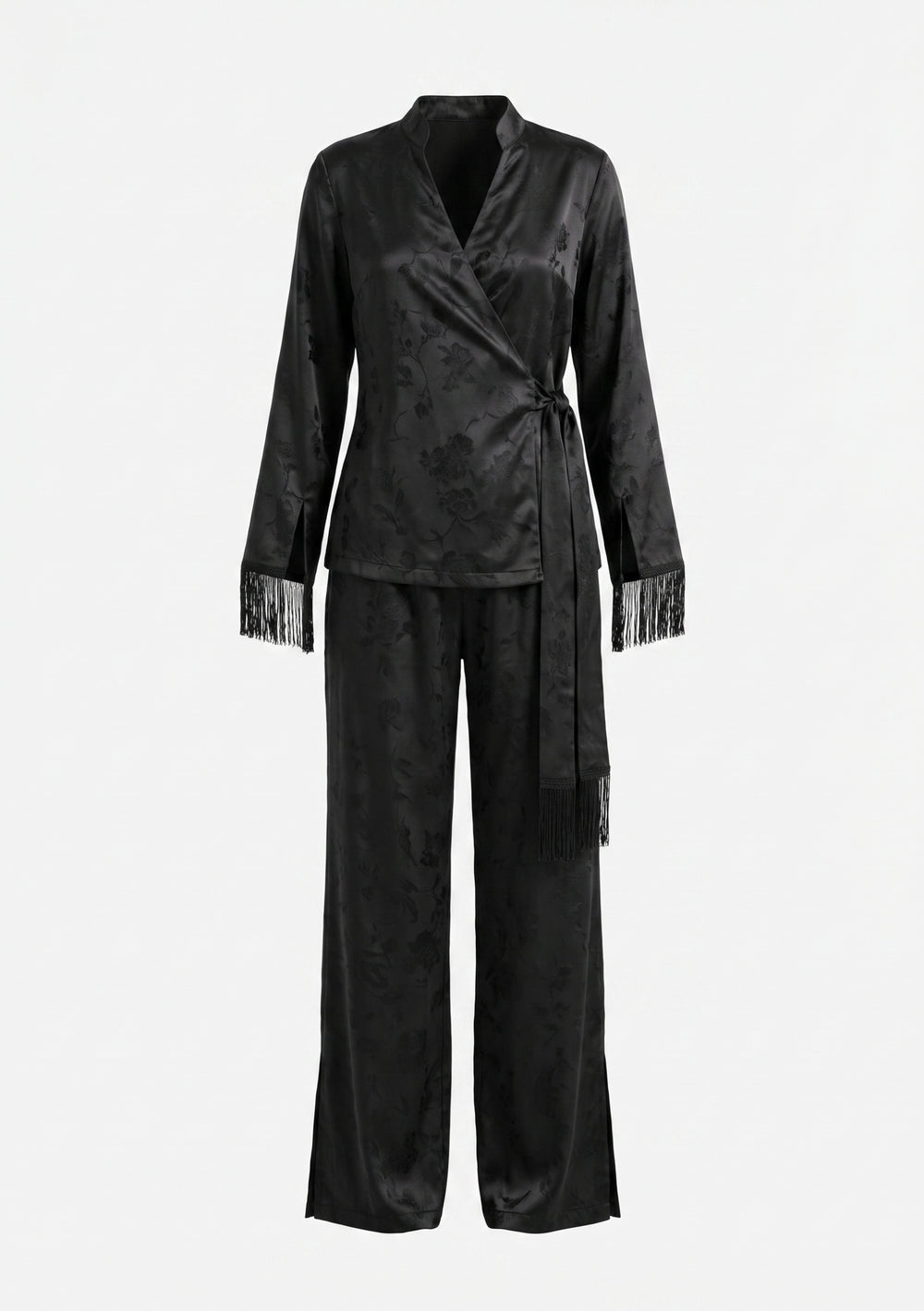 Model in the Tenebrae Set, black satin jacquard wrap top with fringed cuffs and matching wide-leg trousers, full-length three-quarter view with black strappy sandals