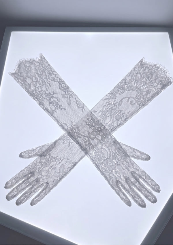 Pair of Etherea white floral lace opera gloves laid crossed on a lightbox, showing the full opera length and eyelash-fringe opening