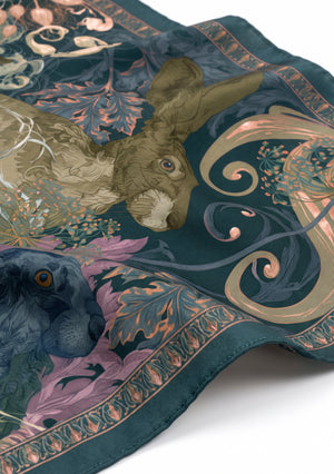 Close view of the Eostra scarf showing the olive and navy hares, the scrollwork and the copper ornamental border