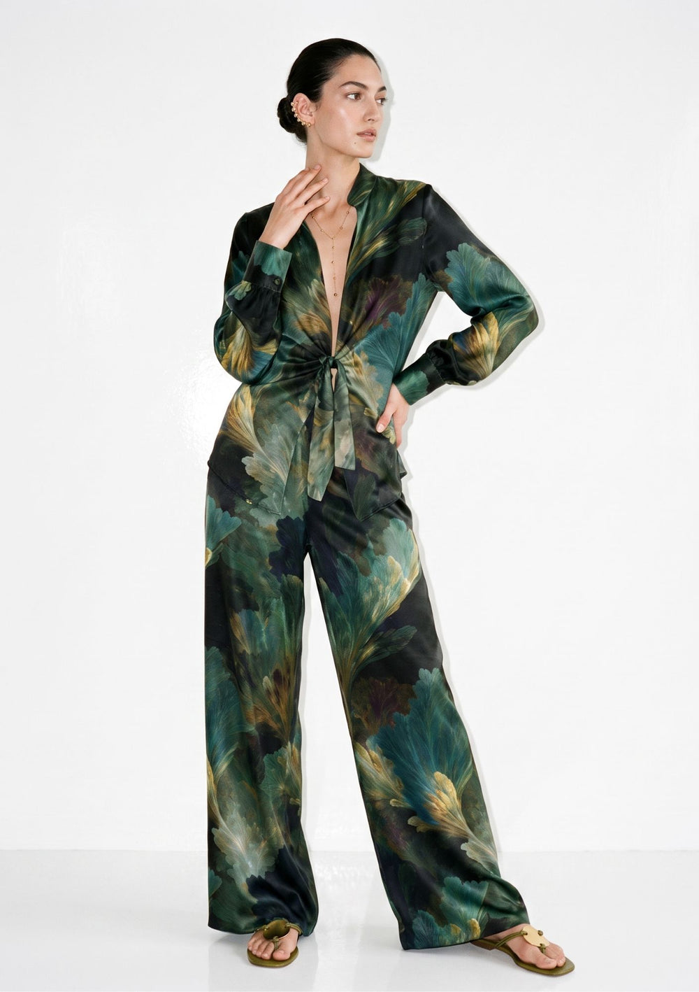 Green botanical print silk pajama set on model, front view, tie-front shirt with deep V neckline knotted at the waist and matching wide-leg trousers