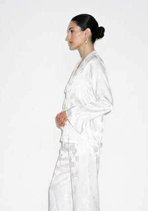 Side view close up of the Moonveil satin shirt showing the tonal floral jacquard, notched collar and ruffle cuff