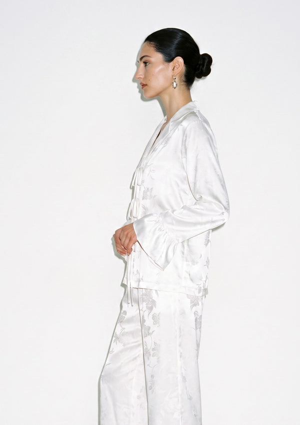 Side view close up of the Moonveil satin shirt showing the tonal floral jacquard, notched collar and ruffle cuff
