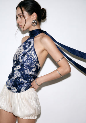 Three-quarter view of the Mirage Peony top with the long navy ties lifted in the air, showing the open side and bare shoulder