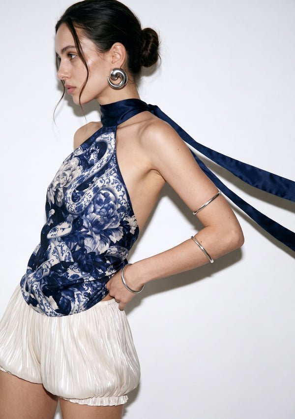 Three-quarter view of the Mirage Peony top with the long navy ties lifted in the air, showing the open side and bare shoulder