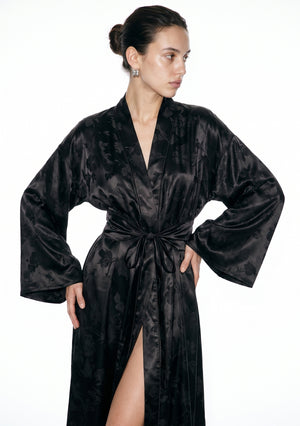 Tenebrae robe worn open at the front, showing the wide belt bow, the bell sleeves and the woven floral catching the light