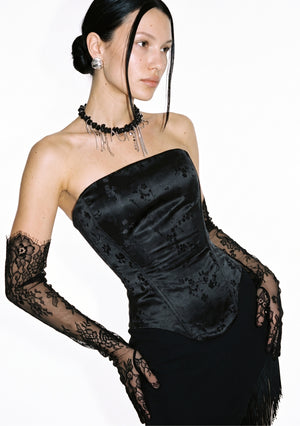Spell Corset black jacquard corset top worn with a black skirt and lace opera gloves, three-quarter view.