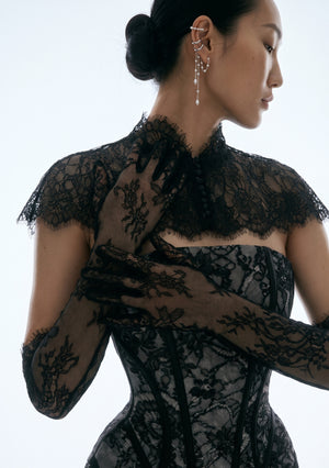 Model wearing the Eclipse black floral lace opera gloves with the coordinating lace corset top, back and shoulder view showing the ruffle trim above the elbow
