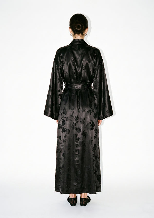Full back view of the Tenebrae robe on model, floor-length with the belt fastened behind and the jacquard floral across the back