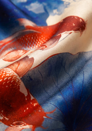 Macro of the Sumi Scarf silk weave, showing the sheen of the fabric and the fine detail of the red koi scales and blue lotus veins