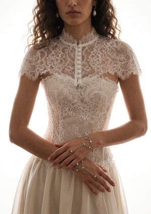 Etherea ivory floral lace capelet front view with high scalloped collar and covered-button front over a lace corset