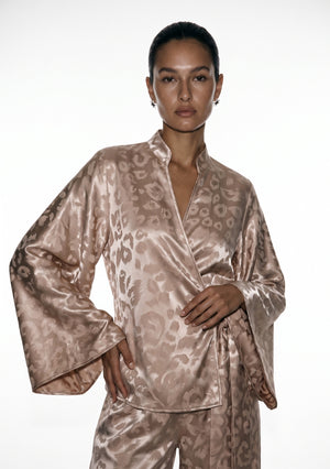 Front view of the Feline wrap shirt, stand collar and crossover front with a bell sleeve held to the side