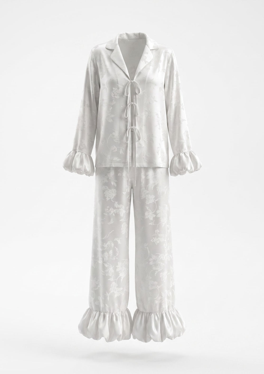 Ivory satin floral jacquard pajama set on model, tie-front shirt with ruffle cuffs and wide-leg trousers with ruffled hem