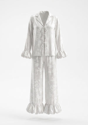 Moonveil ivory satin pajama set shown flat, showing the three satin front ties, notched collar and gathered ruffle cuffs and hem