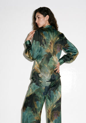 Close view of the Sylvara silk shirt from the back, showing the soft collar, buttoned cuffs and the oversized fan-shaped leaves in emerald and gold